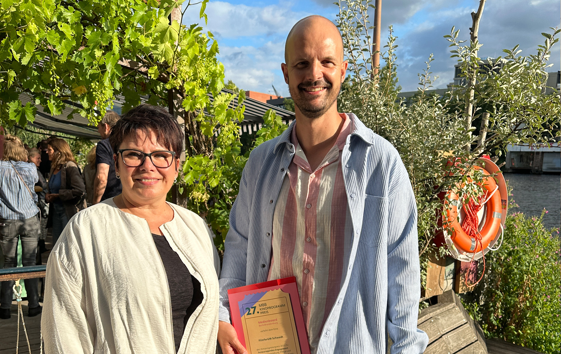 Foto: eine Frau und ein Mann mit der Urkunde in der Hand schauen in die Kamera