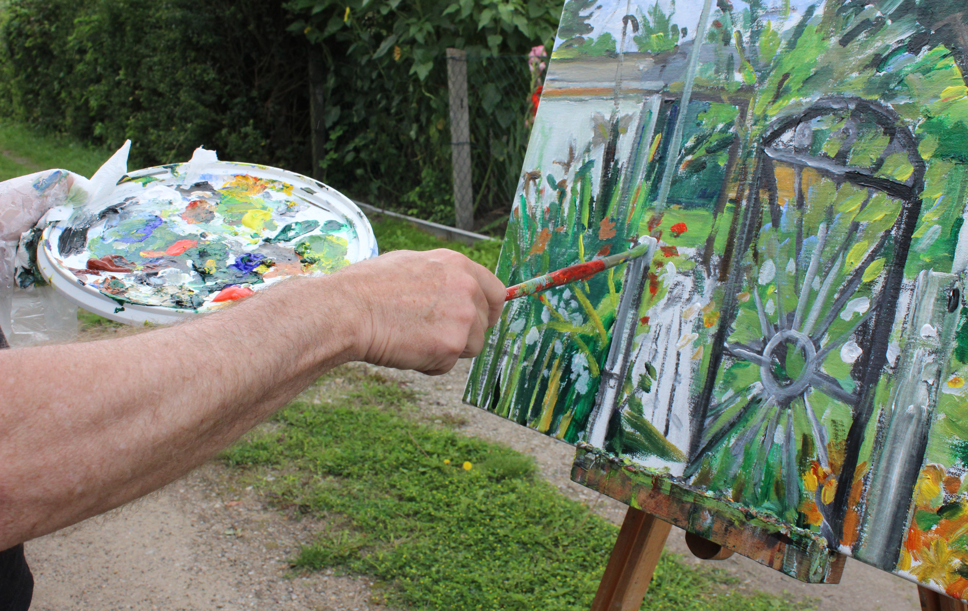 Foto: Bild auf der Leinwand davor Palette und Arm mit Pinsel