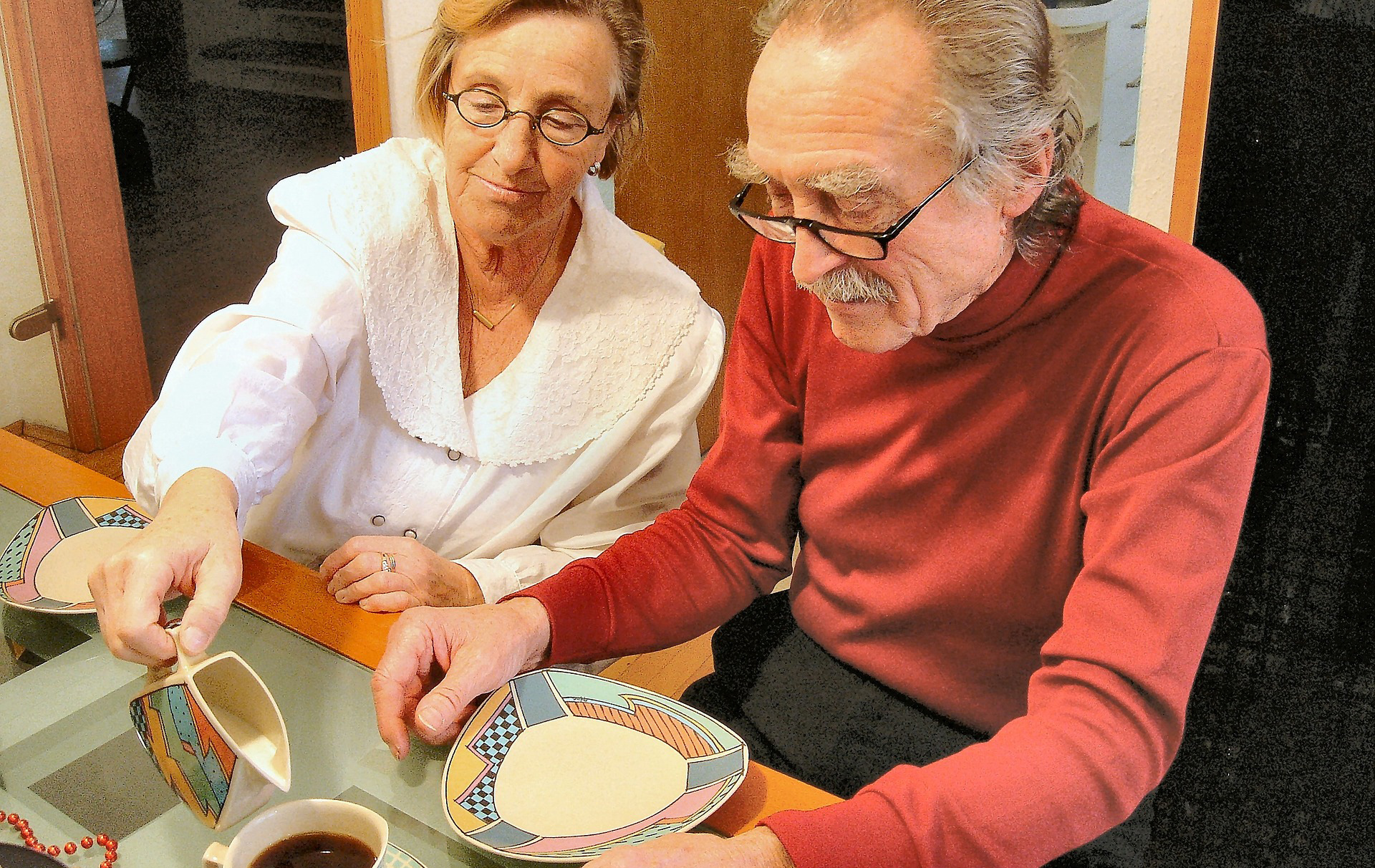 Foto: Frau gießt einem alten Mann Milch in den Kaffee