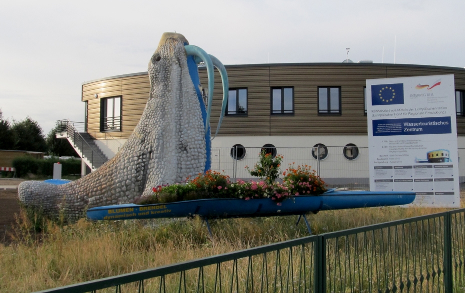 Foto: bepflanztes Kanu mit Walross und Baustellenschild vorm Vereinshauptgebäude.