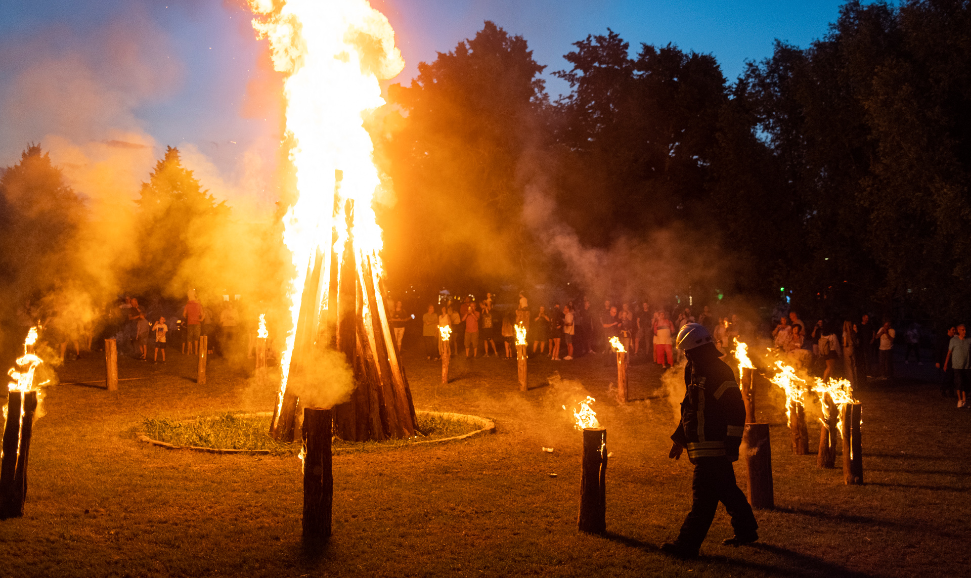 Foto: großes Lagerfeuer mit Feuerwehrmann