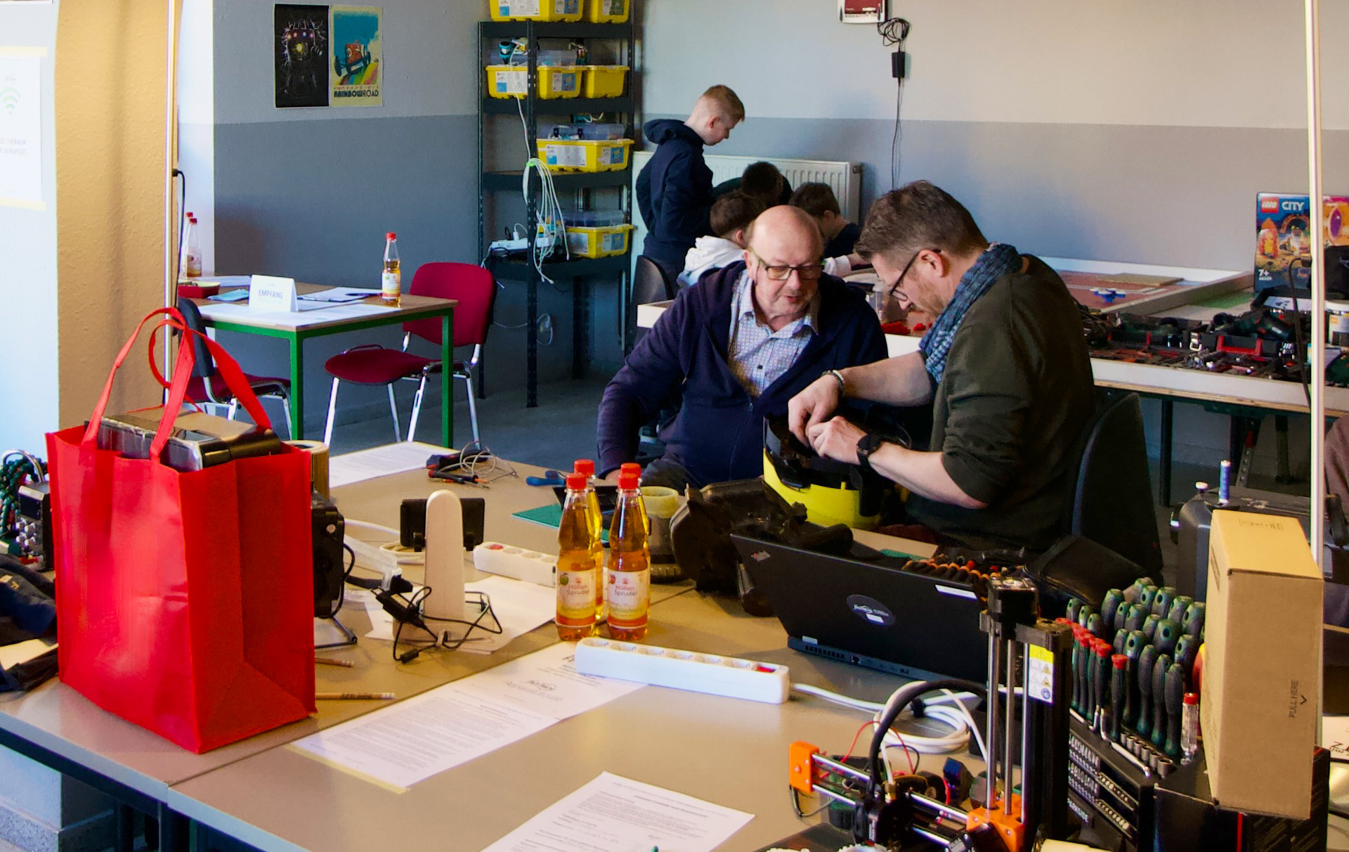 Foto: Blick in die Werkstatt mit 3 Personen beim Reparieren