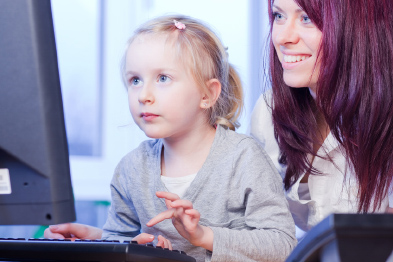 Foto: Mutter schaut ihrer am Computer sitzenden Tochter über die Schulter