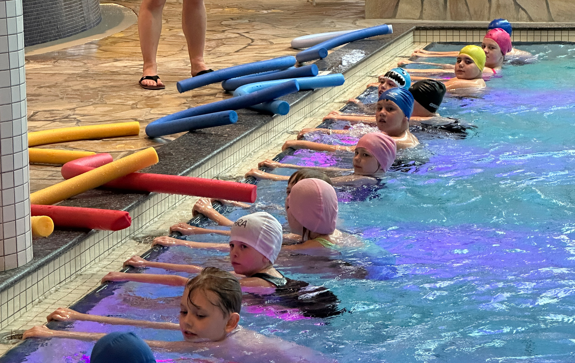 Foto: Kinder halten sich im Wasser am Beckenrand fest