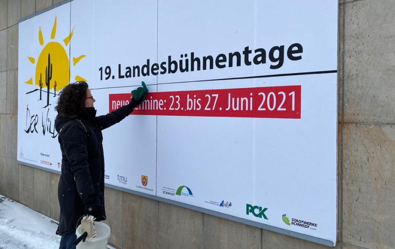 Foto: Eine Frau überklebt ein Plakat.