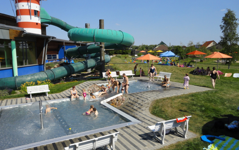 Foto: Spielende Kinder in Planschbecken und Blick zur Liegewiese.