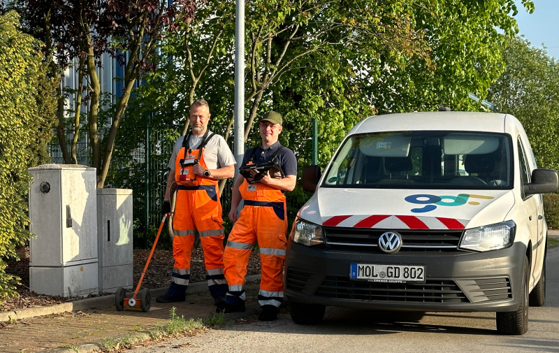 Foto: 2 Kontrolleure vor ihrem Fahrzeug mit ihrem Messgerät