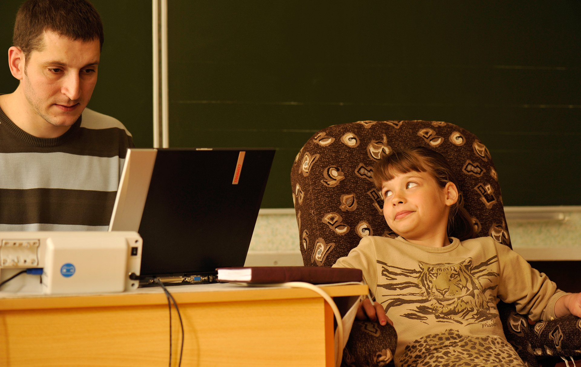 Foto: Mann am Laptop, daneben sitzt ein Mädchen