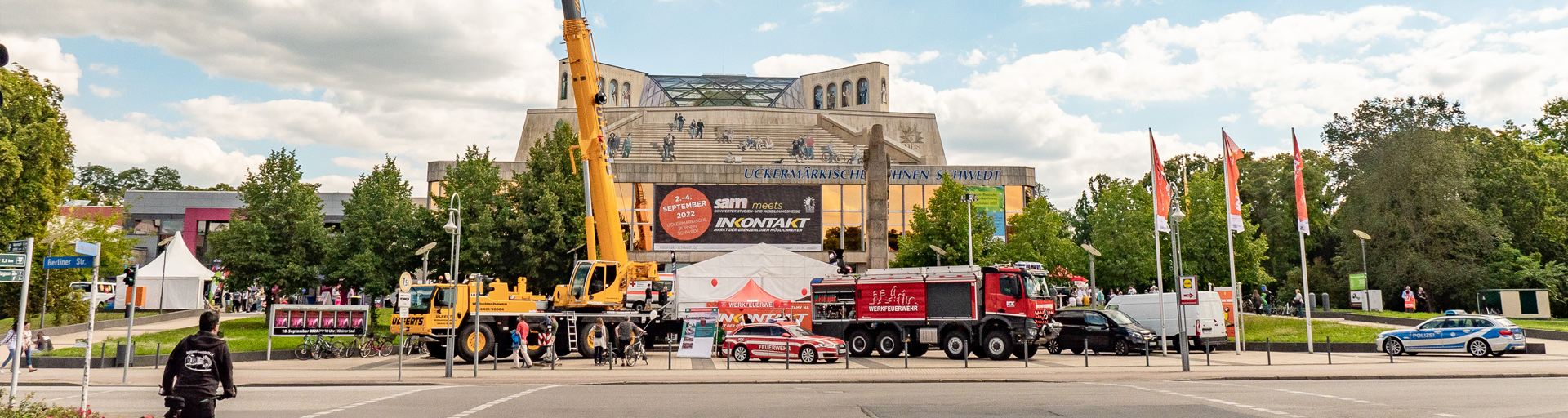 Foto: Theatervorplatz mit Fahrzeugen, Bühne, Ständen