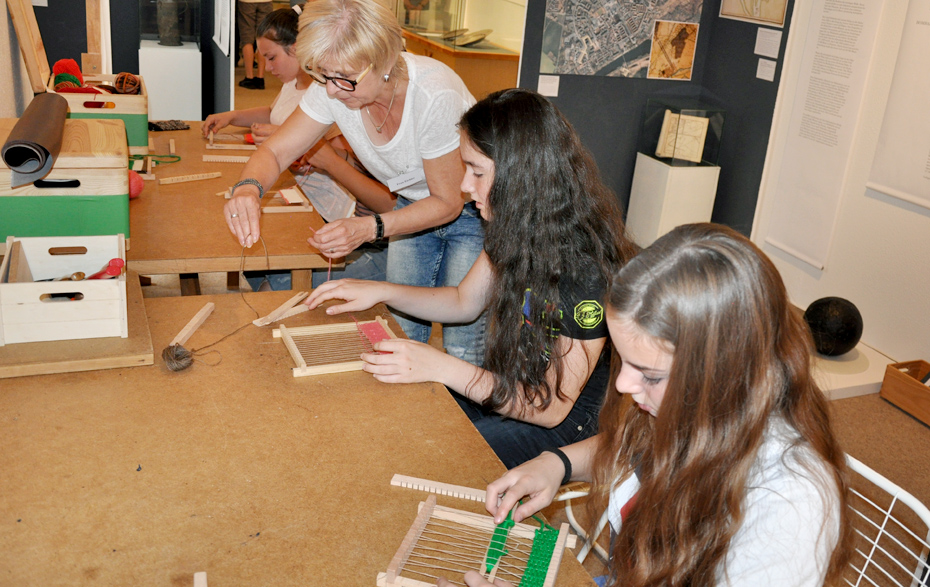 Foto: 3 Mädchen weben unter Anleitung 